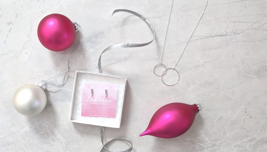 Magenta holiday ornaments with silver jewelry in a gift box and on a marble tabletop