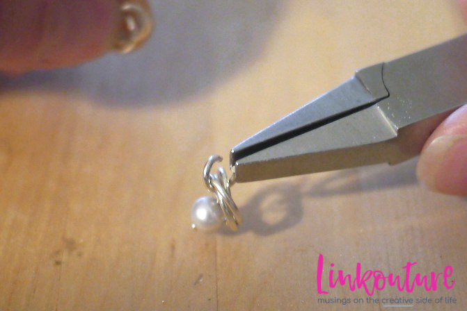 Hand holding jewelry plier with pearl